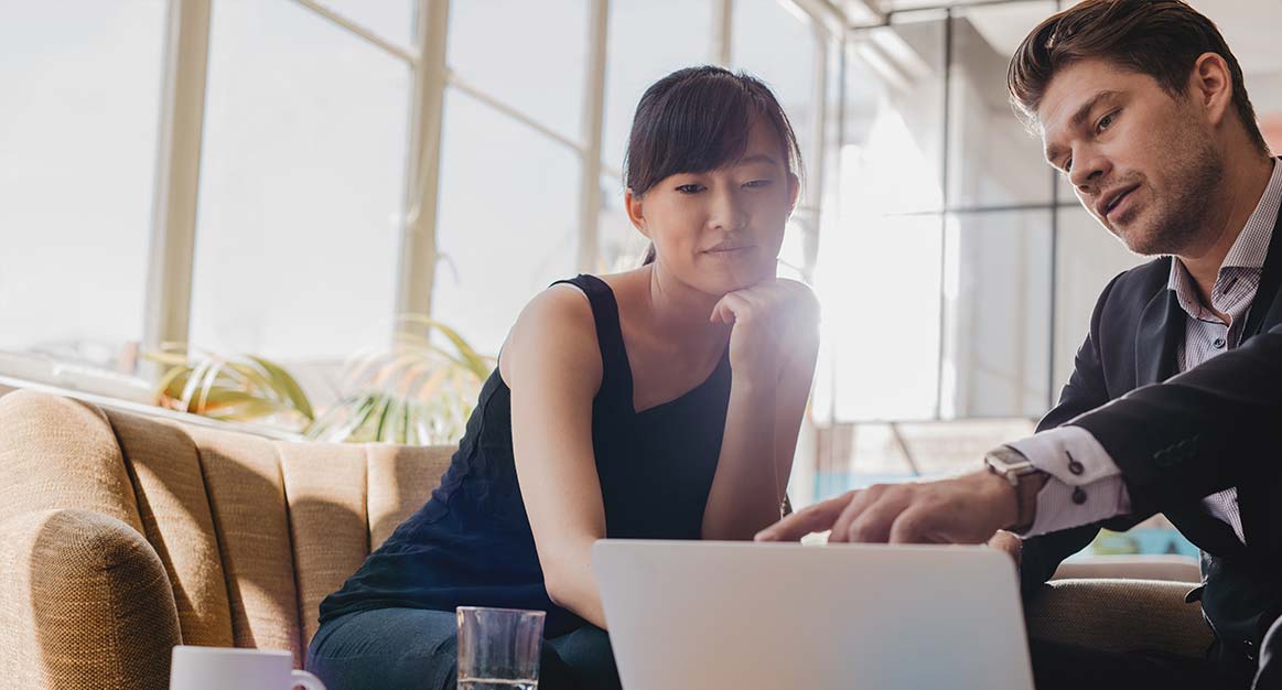 Two people looking at a laptop on comfy chairs